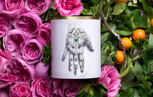 Porcelain candle vessel with illustrated hand in a bed of pink roses and orange branches