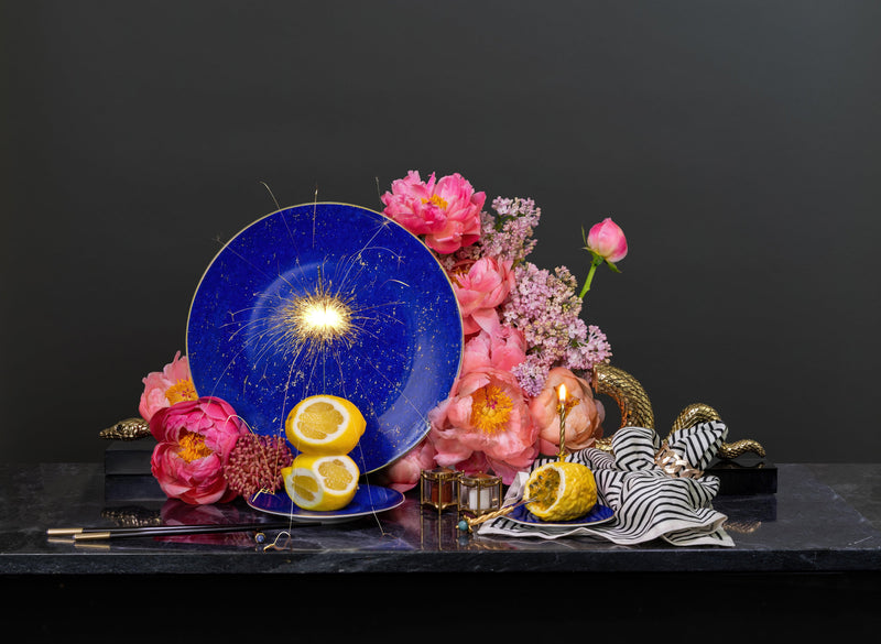 Lapis blue porcelain charger plate, small dish, black wood and gold chopsticks, black + ecru striped linen napkins, arranged with pink flowers