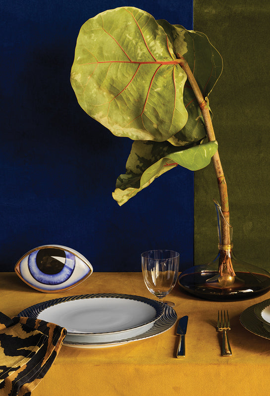 Table setting with a large leaf and decorative eye on a blue and green background