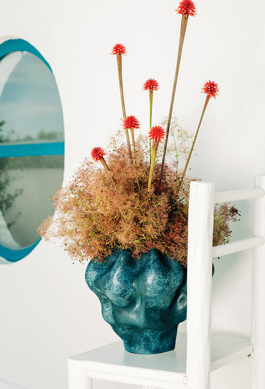 Blue ceramic vase with decorative flowers on a white surface