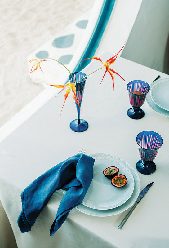 Colorful glassware and a blue napkin on a white tablecloth.