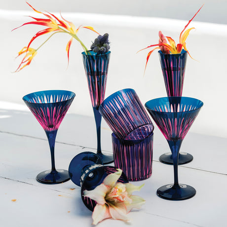 Set of colorful cocktail glasses with floral decorations on a white surface