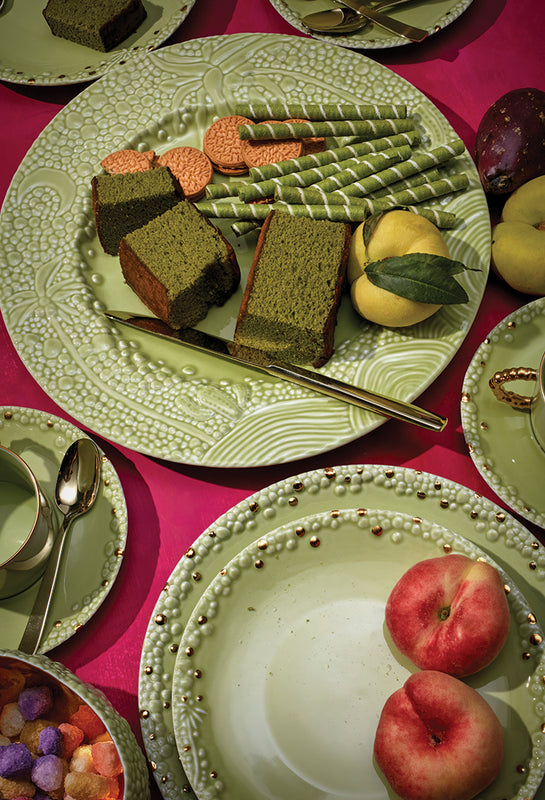 Haas Mojave Matcha Dinnerware Scape on a Fuchsia Table Cloth with lots of poker chips, candy, coffee and green fruit and cakes slices.