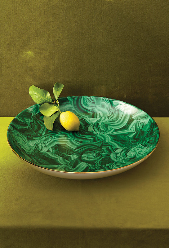 Green decorative plate with a lemon and leaves on a green background