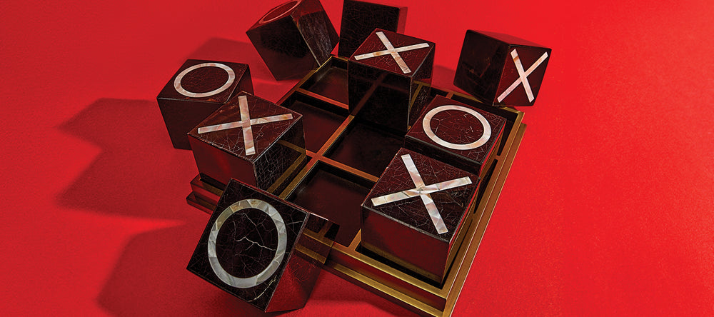 Luxury Tic Tac Toe Block Game with blocks arranged in a dynamic way in a red flat surface with dramatic cast shadow.