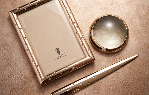 Round magnifying glass with gold border, gold letter opener and gold rectangular picture frame, all embellished with crystals.