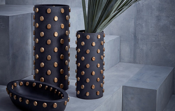 Black porcelain cylinder vases and oval bowl adorned all over with brass ovals.