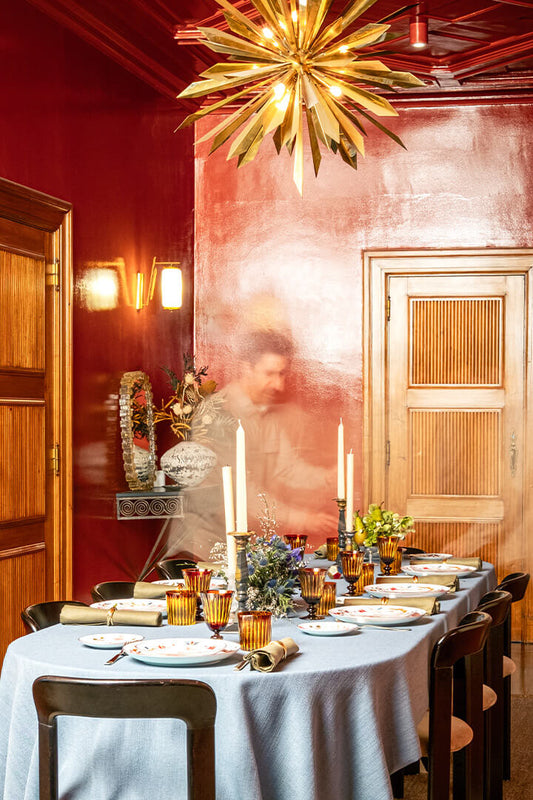 Dining room with a table set for dinner, red walls, and a decorative ceiling light.