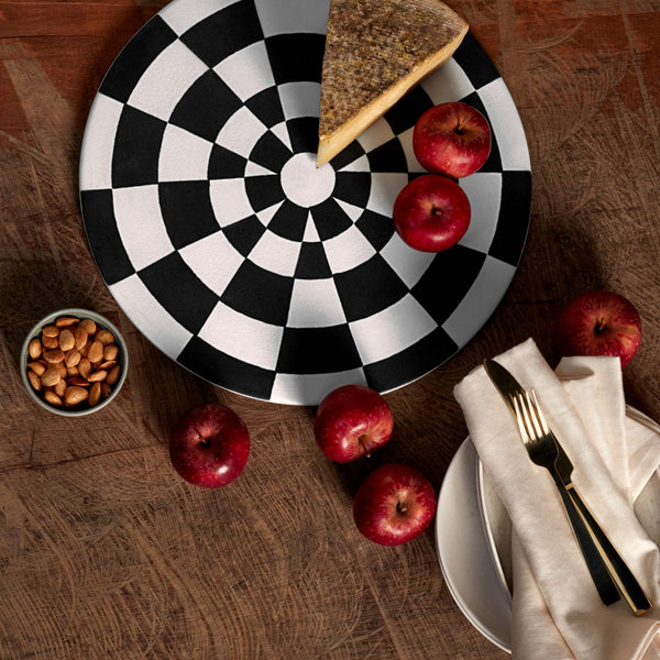 Black and white checkerboard glaze pattern on a low, round porcelain platter styled with red apples