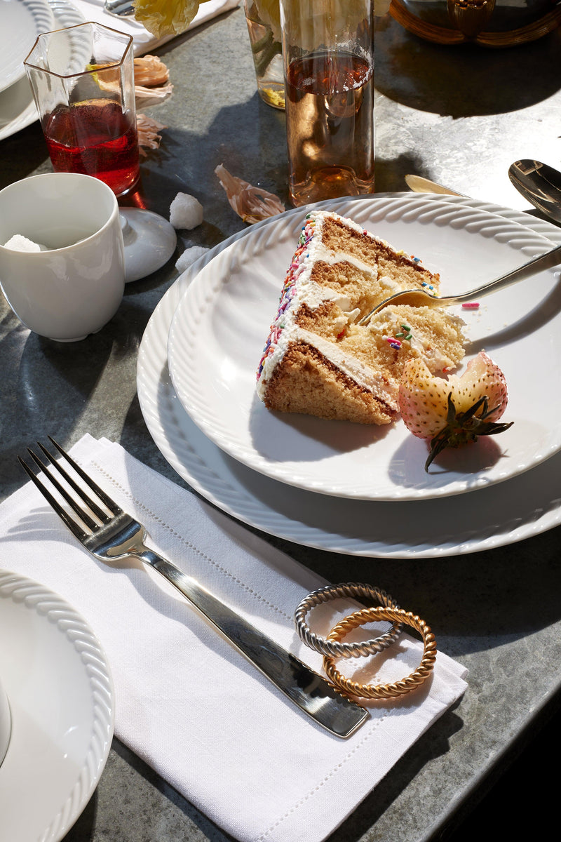 Tabletop with white corde dinnerware, cake and Deco Twist Napkin Jewels in gold and platinum