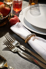 Tabletop with white corde dinnerware, strawberries, and Deco Twist Napkin Jewels in gold and platinum