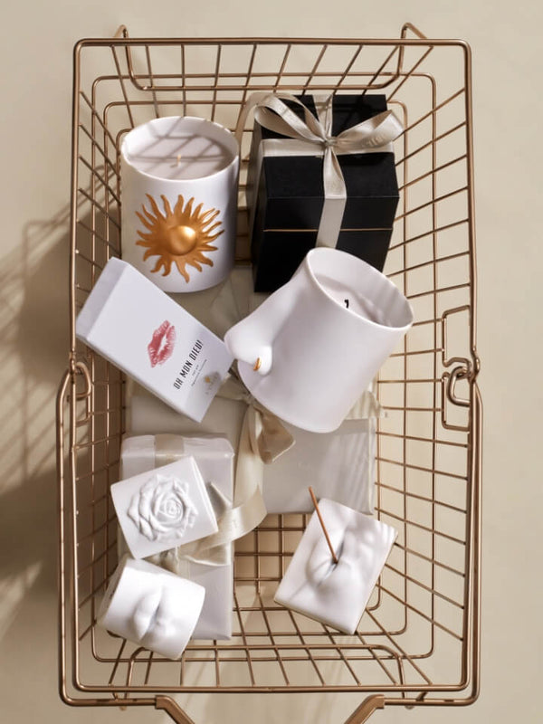 Decorative items including candles and soaps on a wire basket with a neutral background