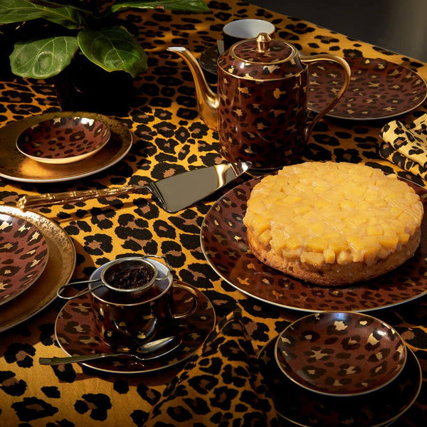 Maximalist tabletop including leopard motif porcelain dinnerware, teapot, teacups + saucer, leopard pattern linen tablecloth