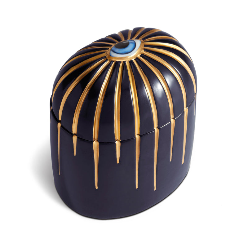 dark blue candle with gold  drip details from an eye motif shot from a top left angle