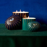Lito Candle Green and Lito Candle 3-wick Blue with eye motif lit up against a blue and green backgro