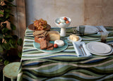 Table set with Terra bronze round placemat, Terra leather and seafoam dinnerware, linen sateen green and yellow waves tablecloth